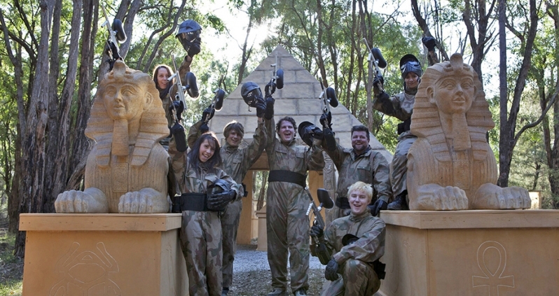A paintball group celebrating among temple game-zone props